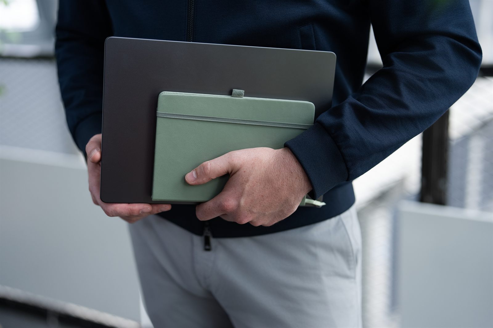 Laptop und grünes Notizbuch unter dem Arm getragen