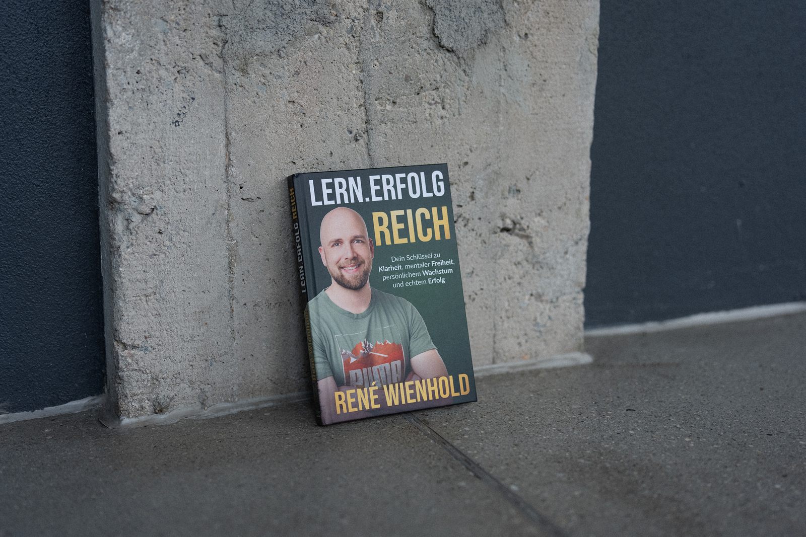 Das Buch Lern.Erfolg.Reich lehnt an einer Betonwand